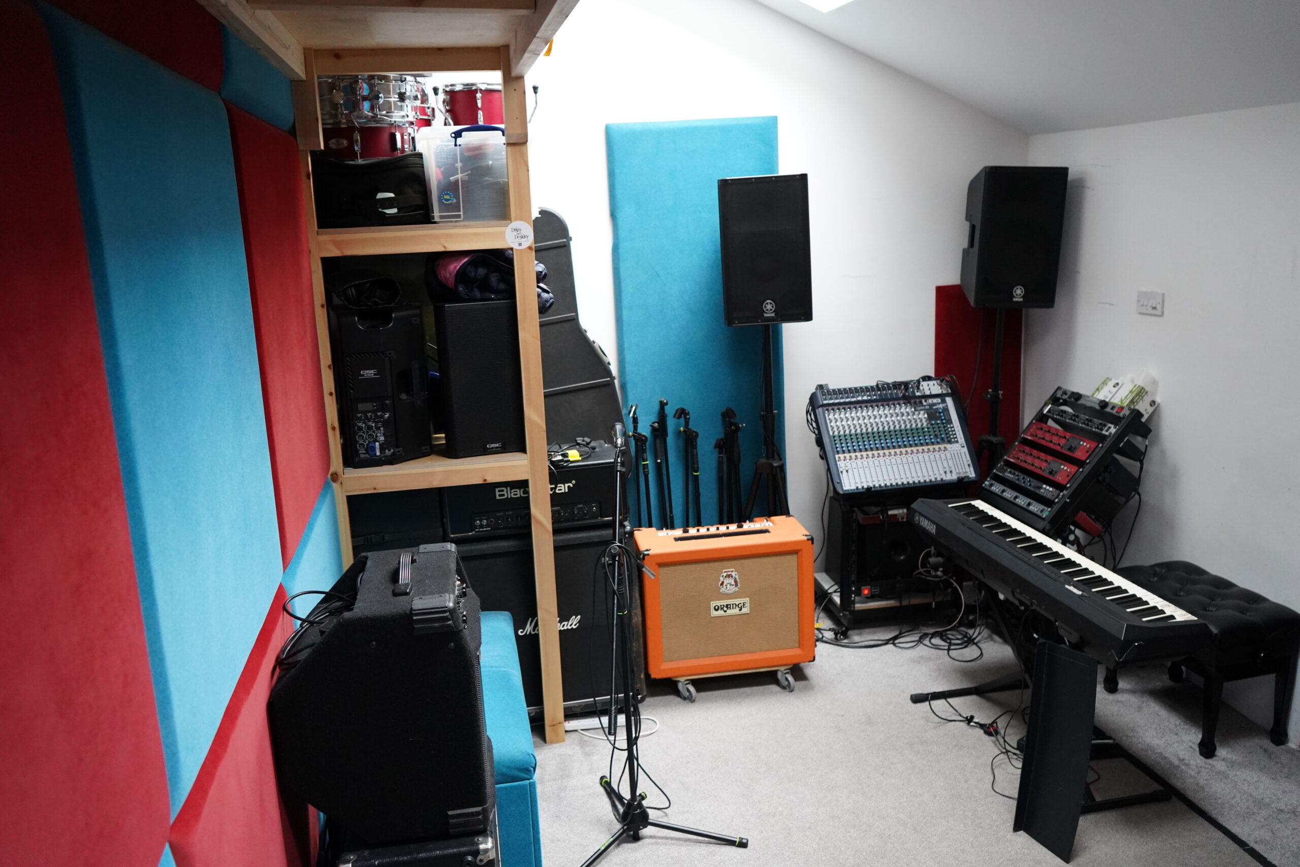 Wide view of the studio from the opposite end, showing acoustic panelling and backline