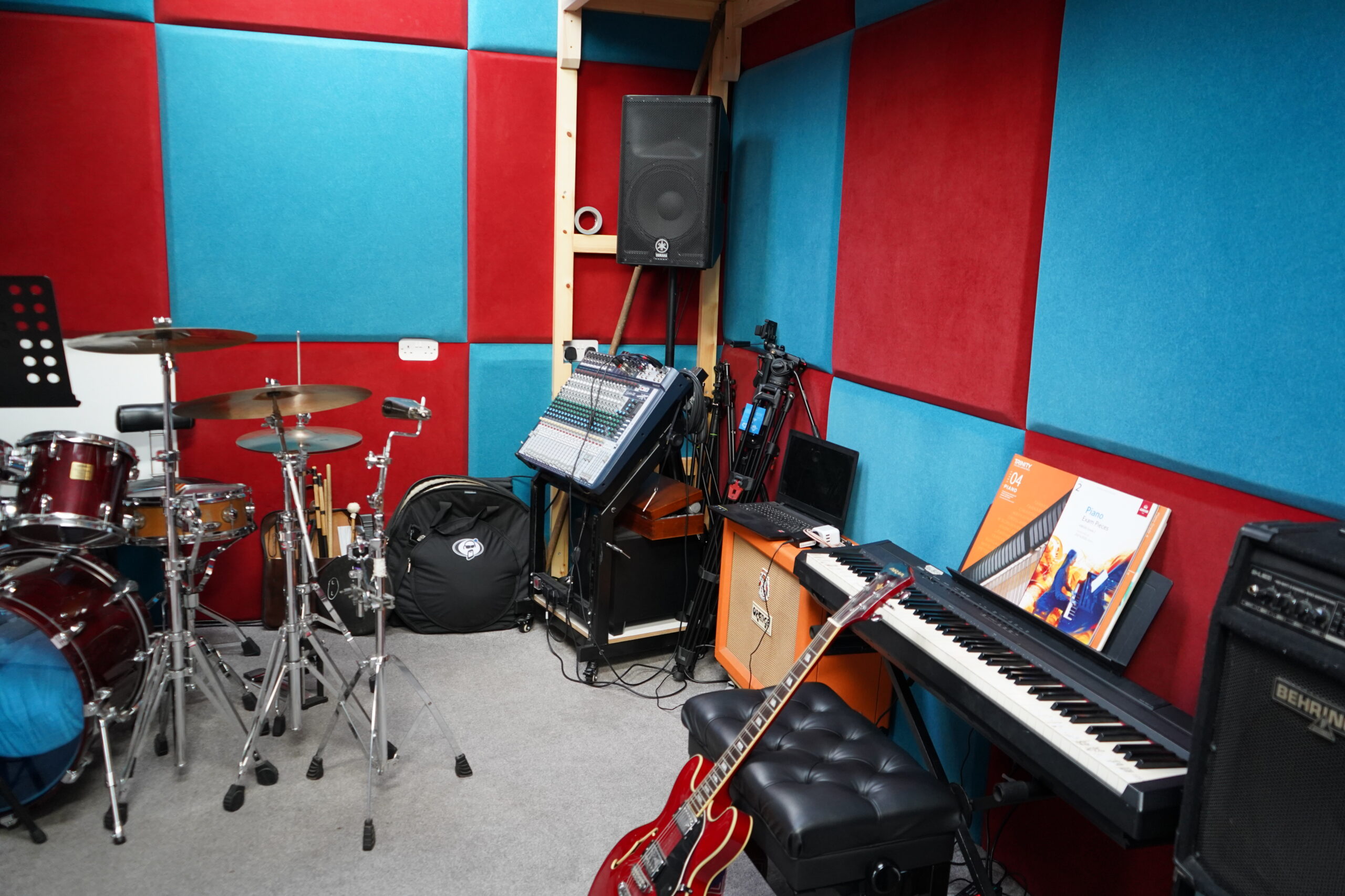 Harrow Music Studio rehearsal room with drum kit, mixing desk, digital piano, guitar amps and acoustic wall panels